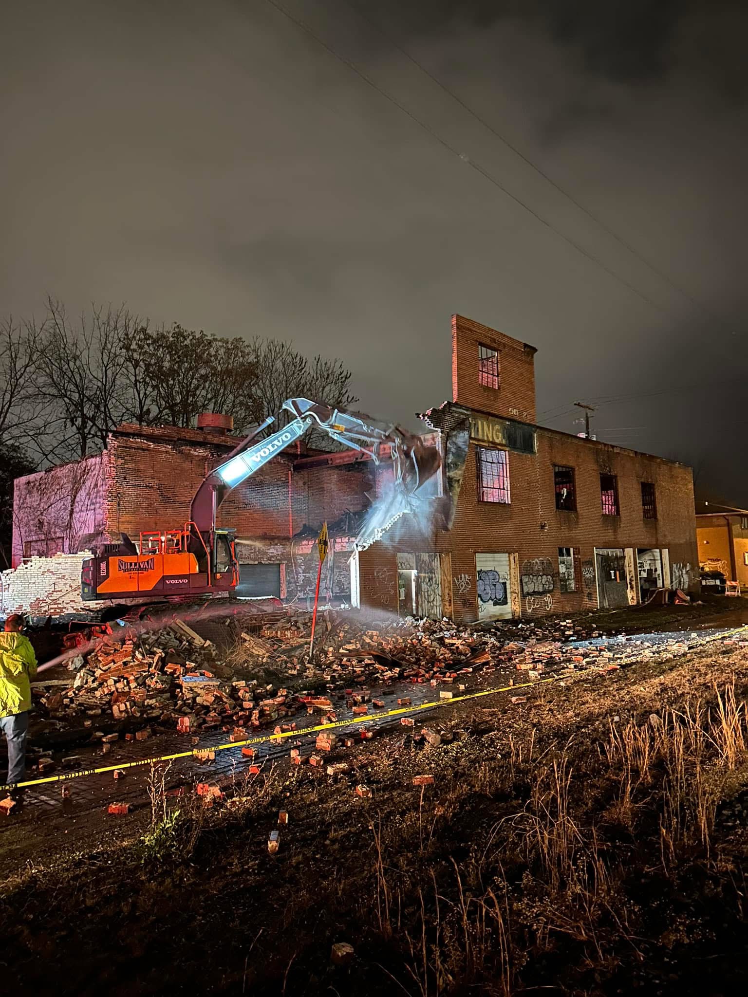Two excavators demolishing a multistory building at a Sullivan Excavating jobsite.